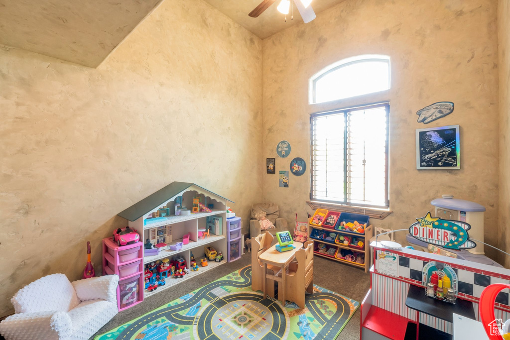 Playroom with healthy amount of natural light, a ceiling fan, carpet floors, and a towering ceiling