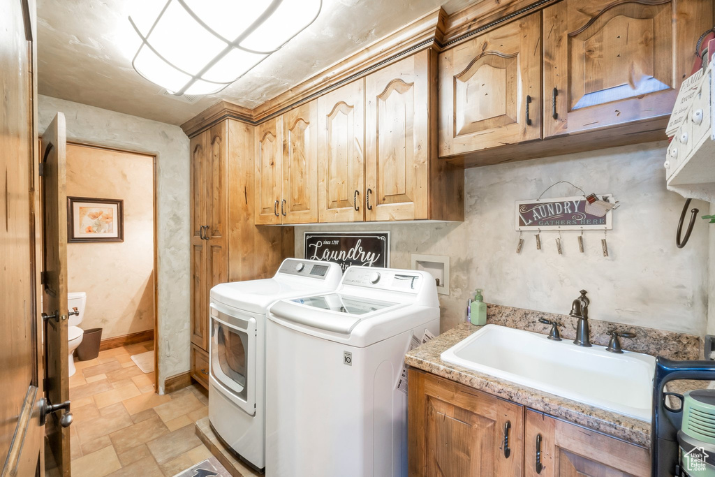 Laundry room with cabinet space, independent washer and dryer, and stone finish flooring