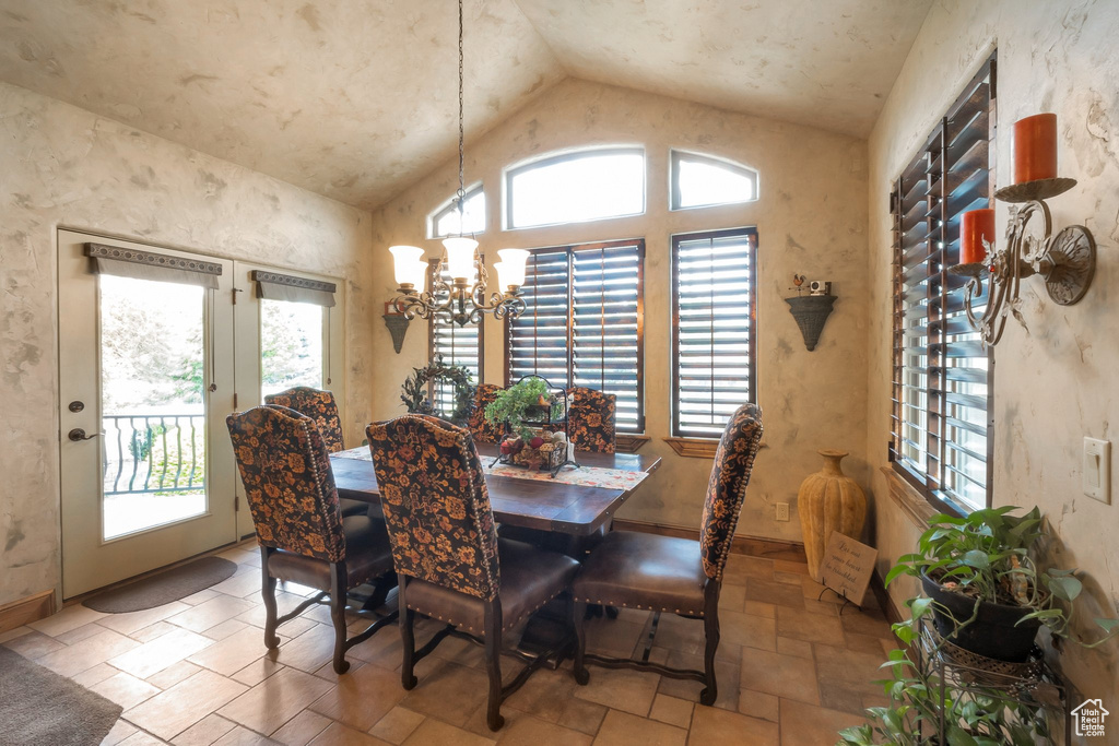 Dining room with vaulted ceiling, plenty of natural light, stone tile flooring, and a chandelier