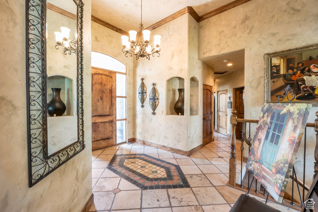 Entrance foyer featuring ornamental molding, a chandelier, and a towering ceiling