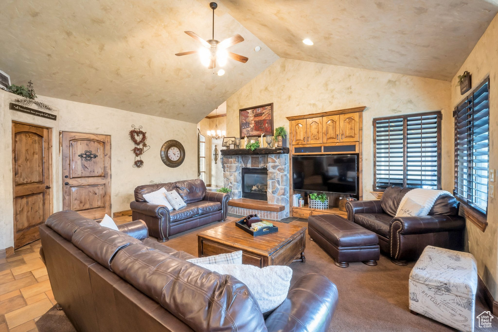 Living area featuring lofted ceiling, a ceiling fan, stone tile flooring, and a stone fireplace