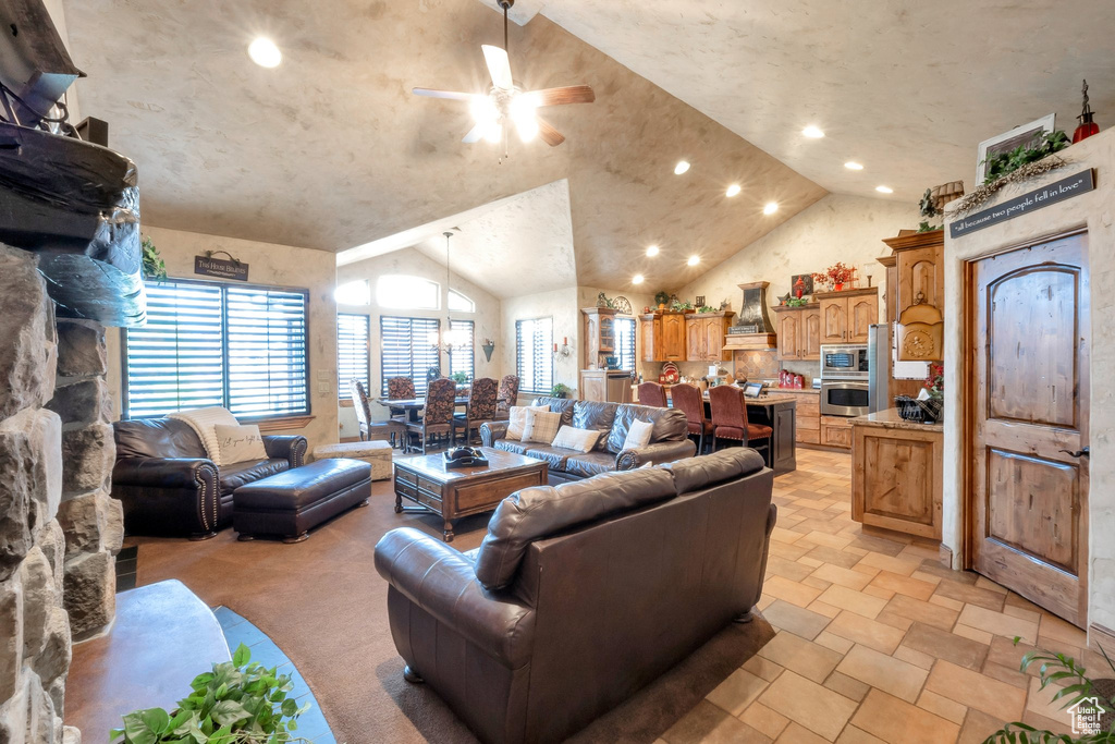 Living room featuring ceiling fan, lofted ceiling, recessed lighting, and light stone finish flooring