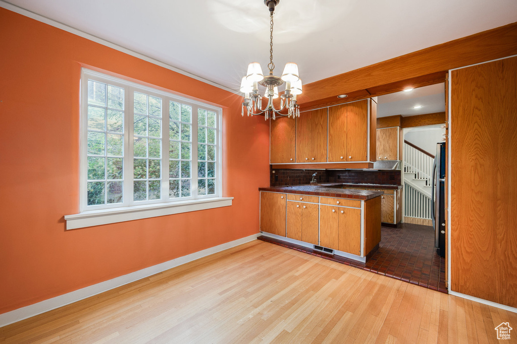 Kitchen featuring brown cabinetry, a chandelier, dark countertops, and plenty of natural light