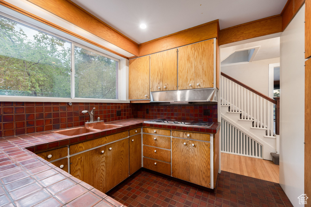 Kitchen with tile countertops, under cabinet range hood, and tasteful backsplash