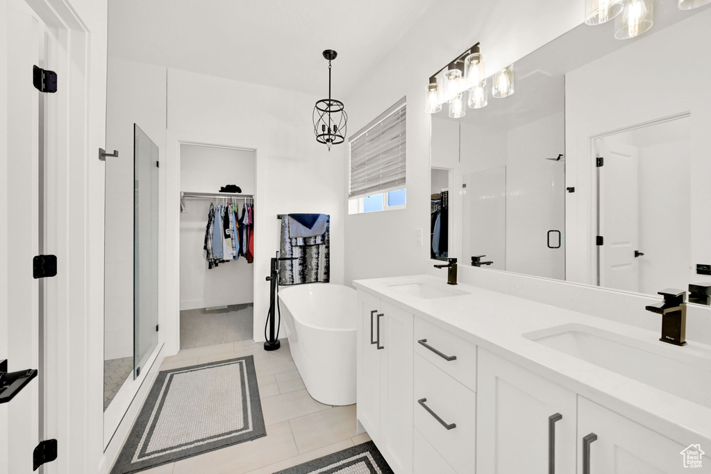 Bathroom with a shower stall, double vanity, a walk in closet, a freestanding bath, and tile patterned floors
