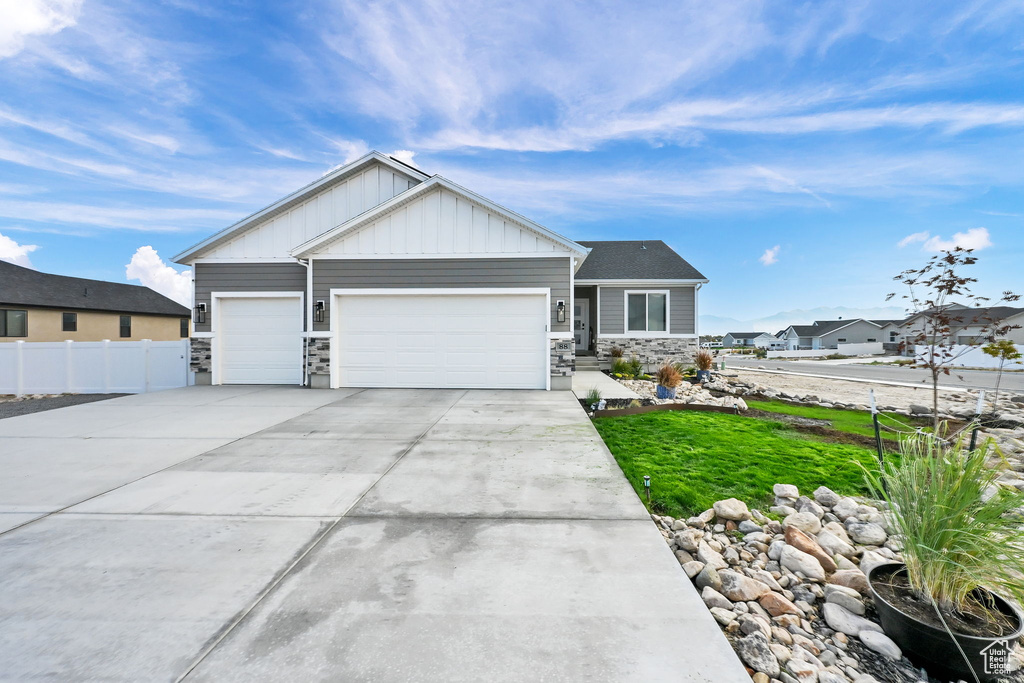 Craftsman-style home with stone siding, an attached garage, board and batten siding, and driveway