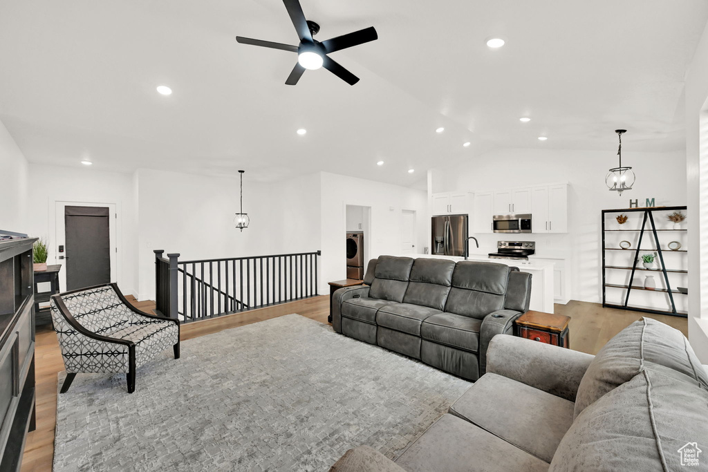 Living room with light wood finished floors, a ceiling fan, recessed lighting, vaulted ceiling, and washer / clothes dryer