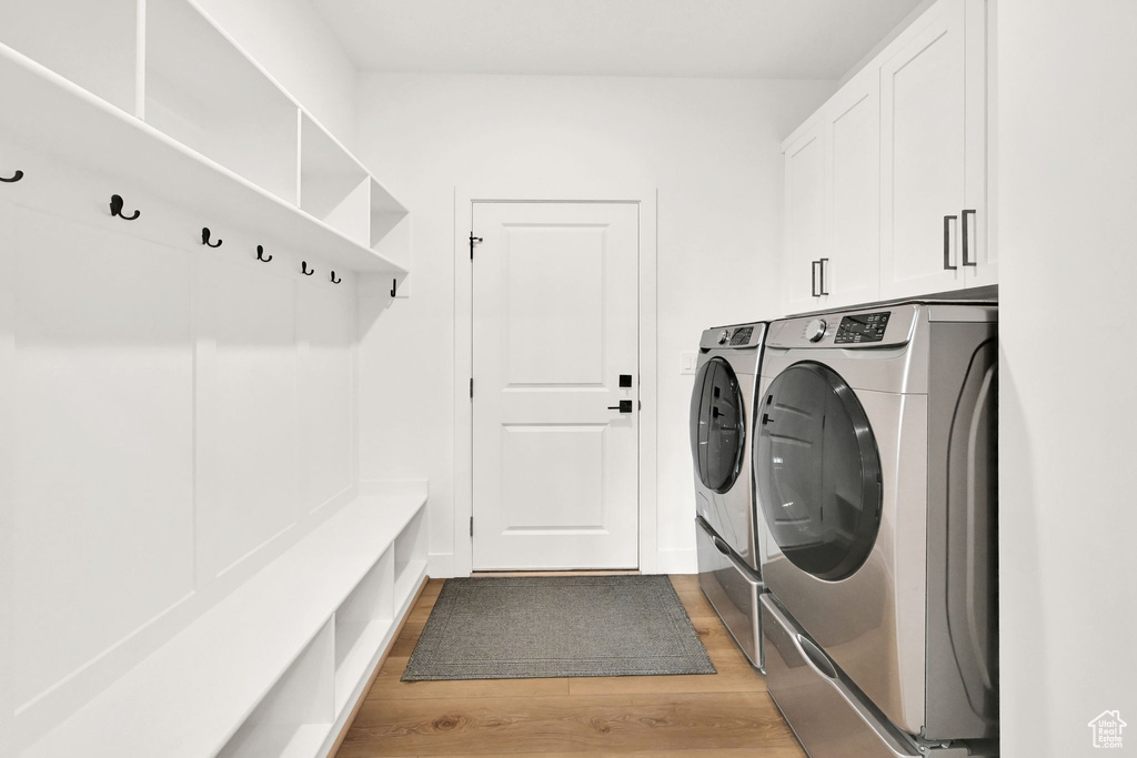 Washroom featuring washer and dryer, light wood finished floors, and cabinet space