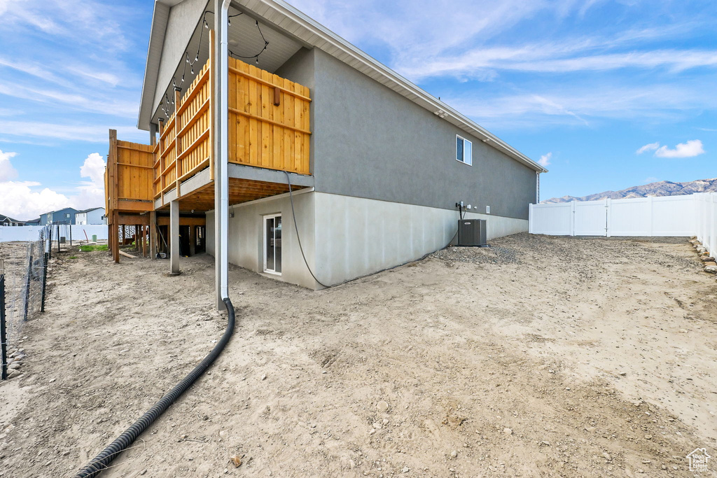 Rear view of house with stucco siding and a deck with mountain view
