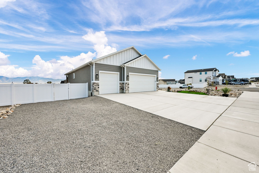 View of home's exterior featuring driveway, a garage, board and batten siding, stone siding, and a residential view