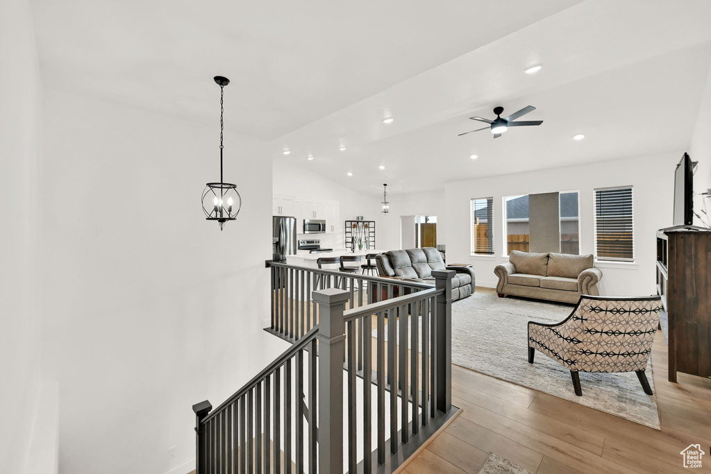 Stairway with wood finished floors, a ceiling fan, recessed lighting, and vaulted ceiling
