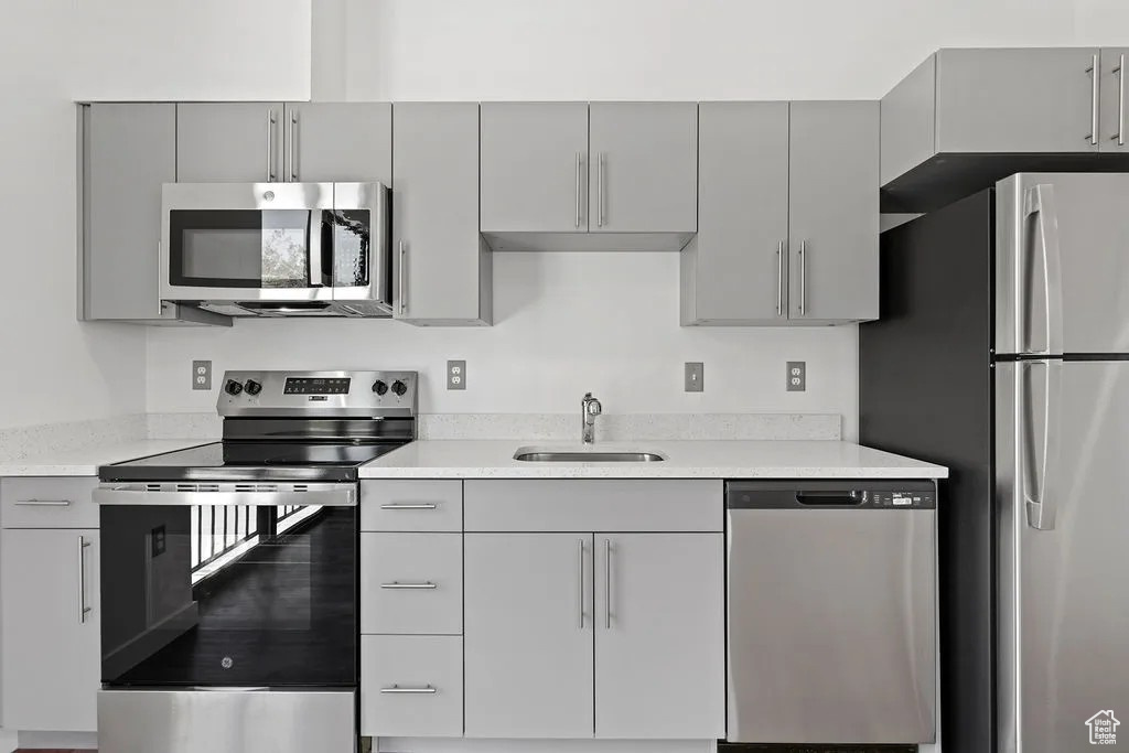 Kitchen featuring stainless steel appliances, gray cabinets, and light countertops