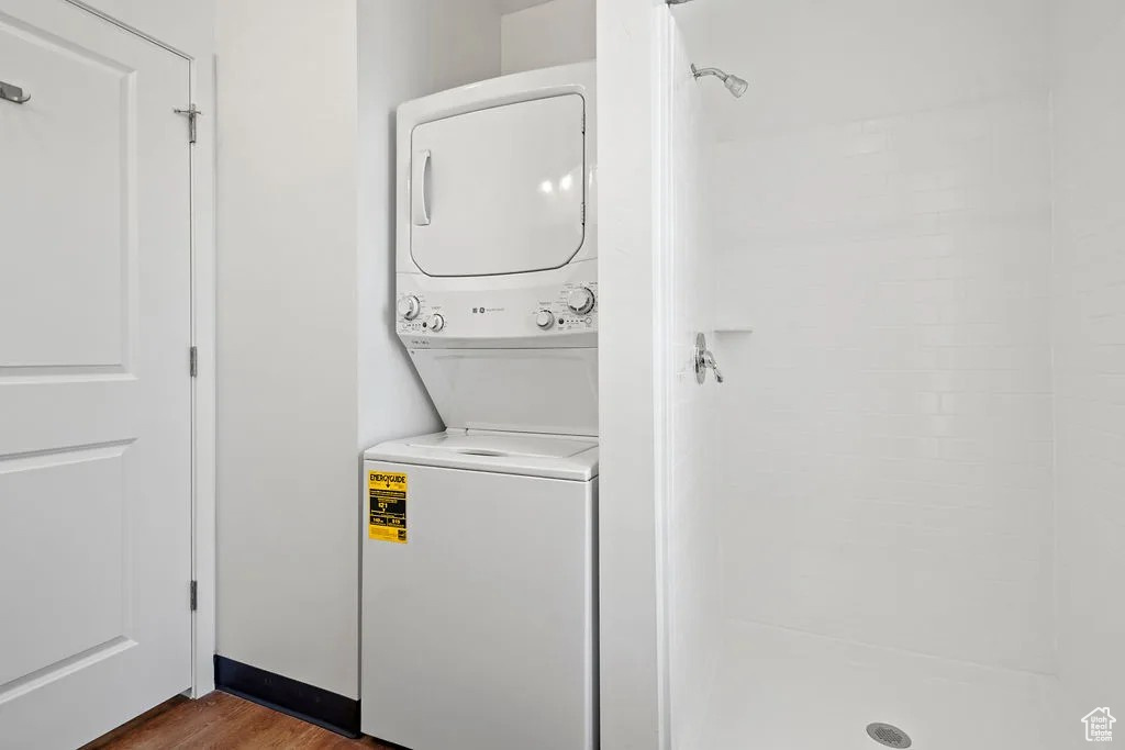 Washroom with estacked washer and dryer and dark wood-type flooring