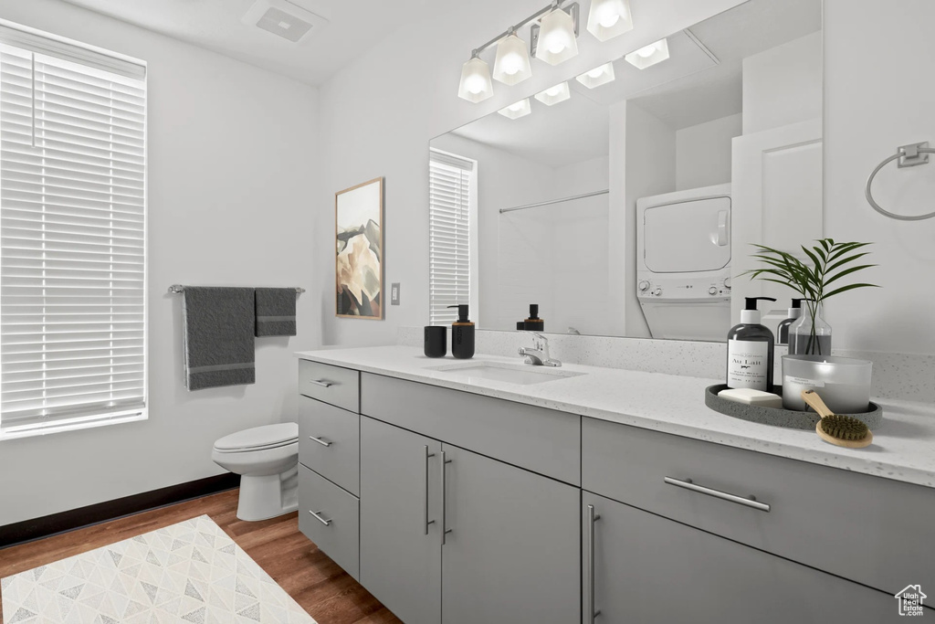 Full bathroom featuring stacked washing machine and dryer, vanity, and wood finished floors
