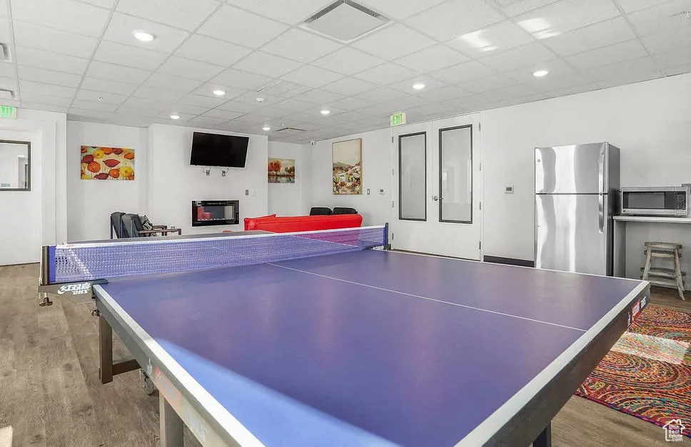 Recreation room featuring wood finished floors and a paneled ceiling