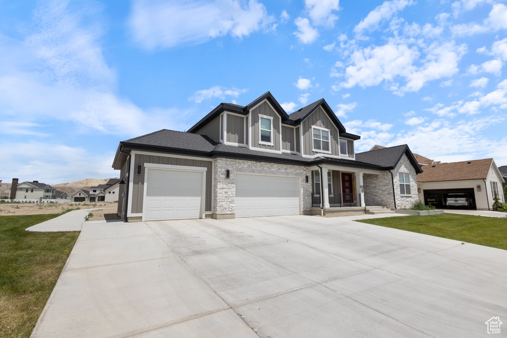 View of front of house featuring driveway, a front yard, an attached garage, and board and batten siding