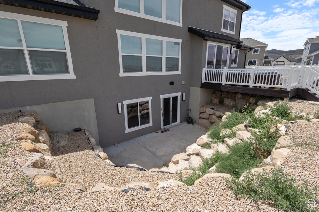 Rear view of property featuring stucco siding, a wooden deck, and a patio
