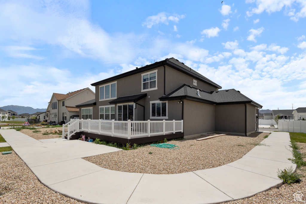 Rear view of property featuring a residential view, a wooden deck, and stucco siding