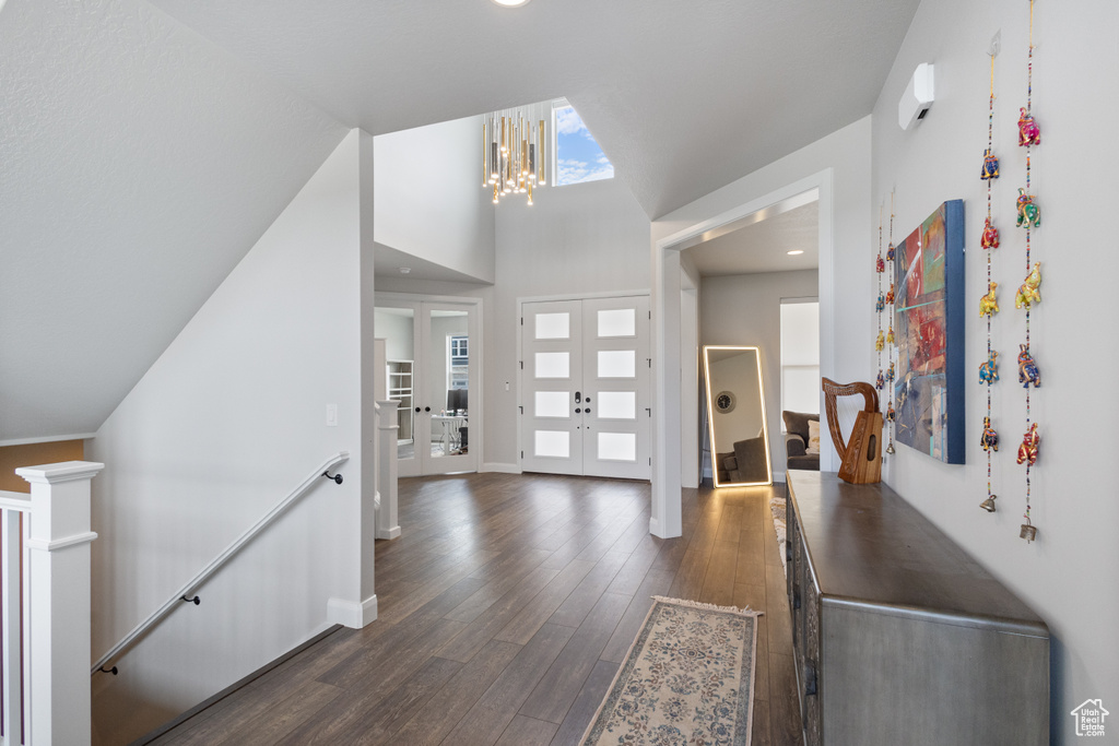 Entrance foyer featuring dark wood-style floors, vaulted ceiling, and a chandelier