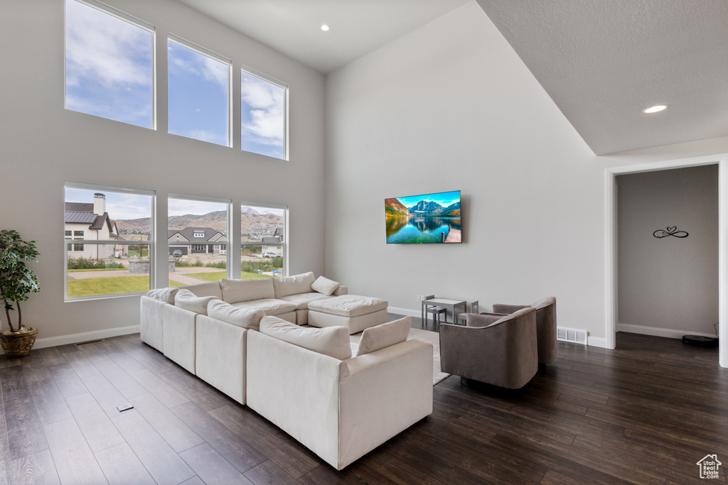 Living room with a high ceiling, dark wood finished floors, and recessed lighting