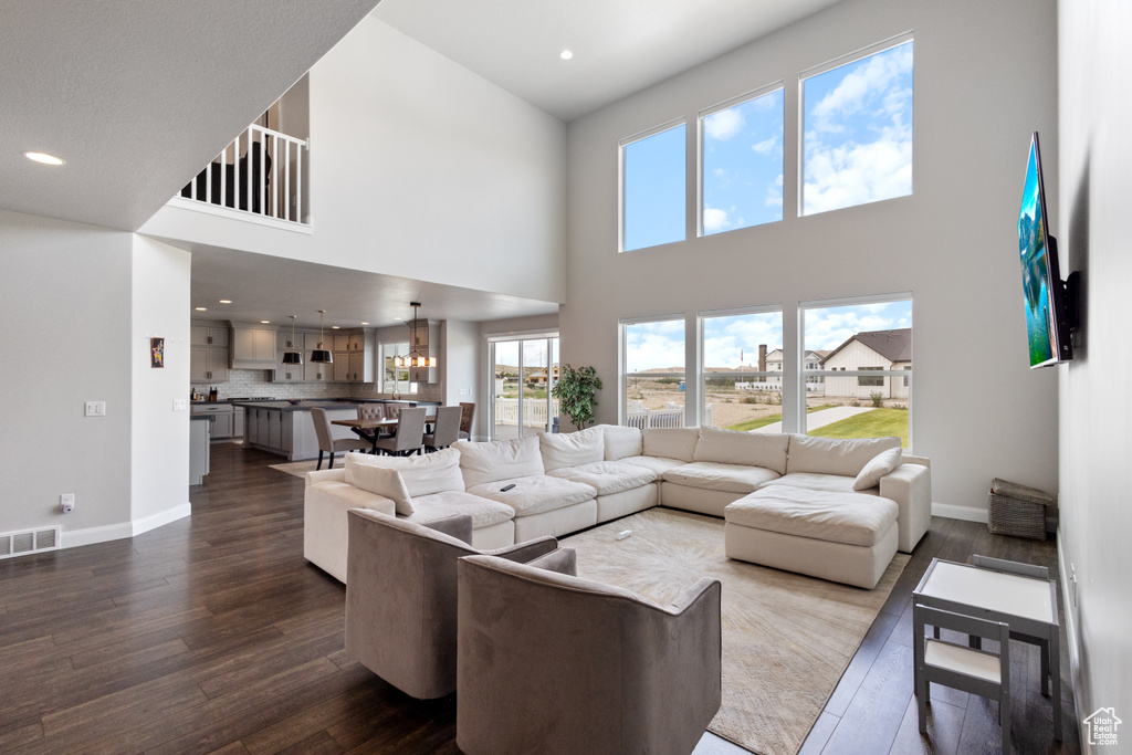 Living room featuring dark wood finished floors, a high ceiling, and recessed lighting