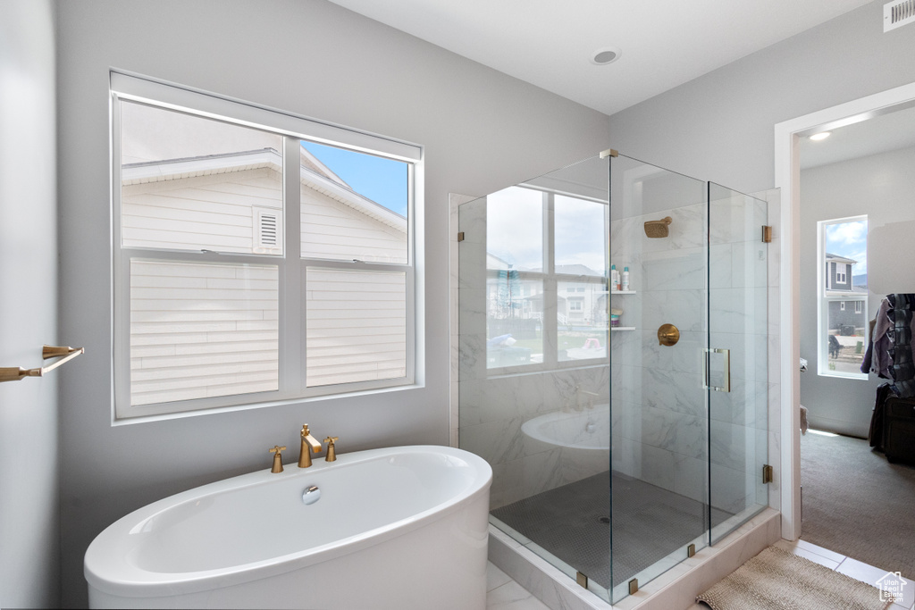 Full bath featuring plenty of natural light, a freestanding tub, a shower stall, and tile patterned flooring