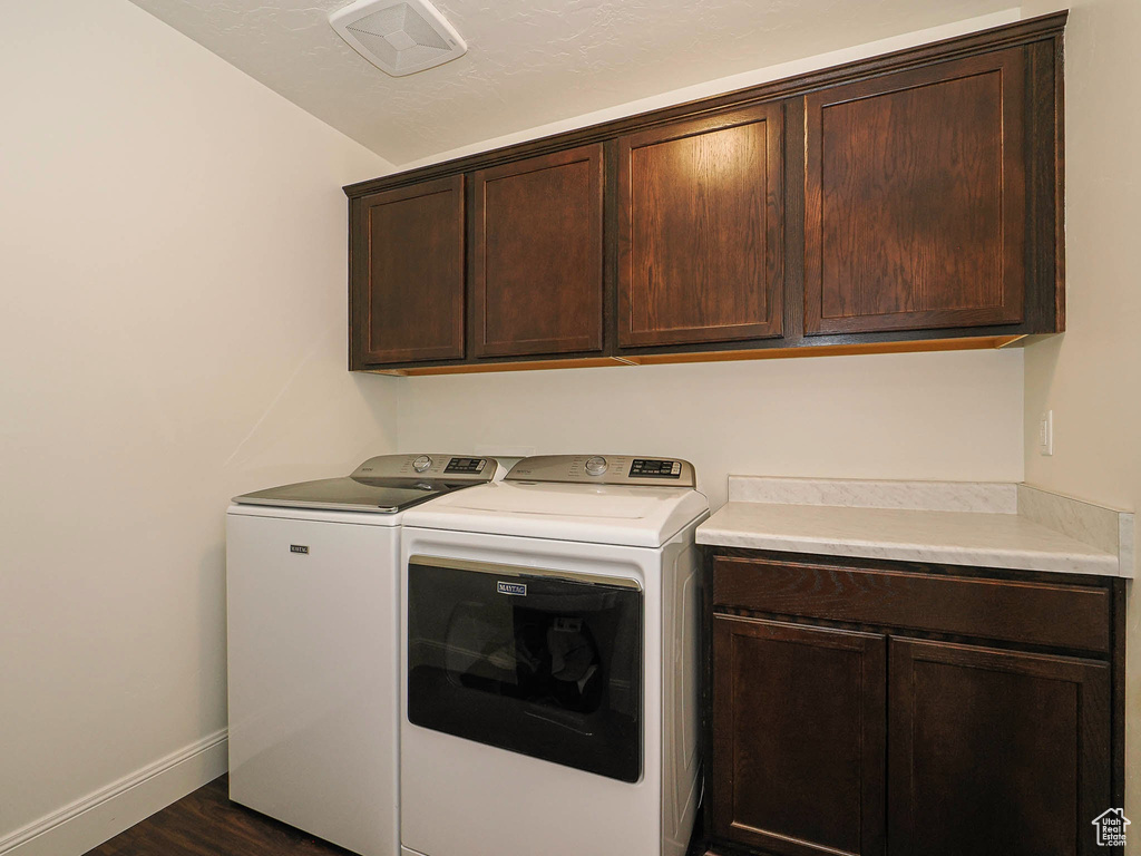 Washroom with cabinet space, separate washer and dryer, and dark wood-style flooring