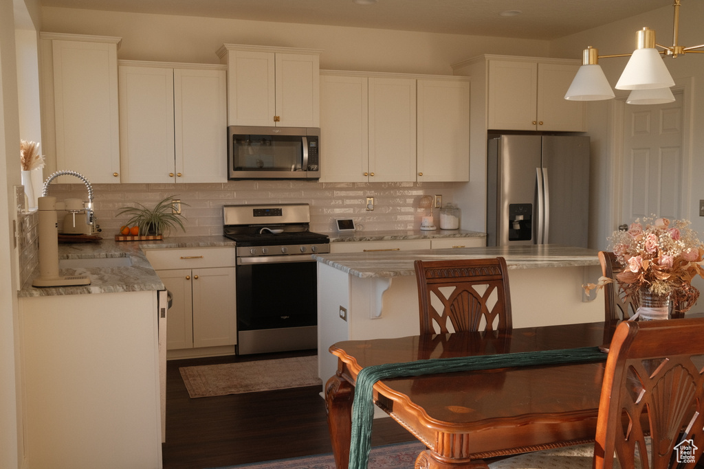 Kitchen with stainless steel appliances, backsplash, dark wood-style floors, and white cabinetry