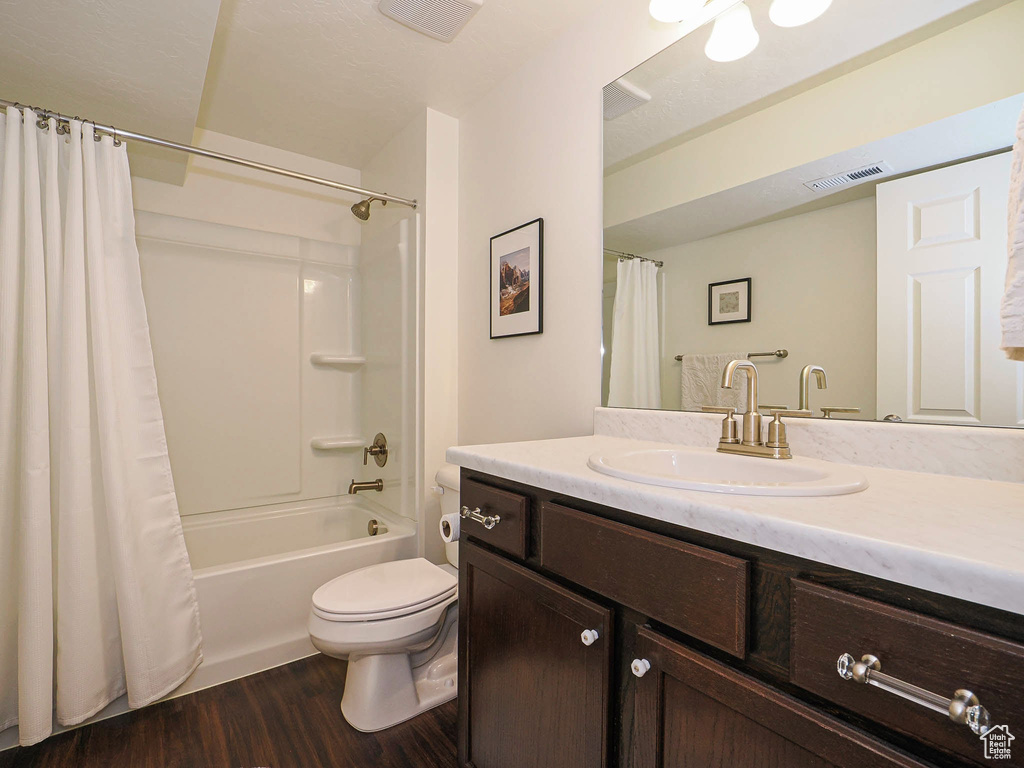 Bathroom featuring wood finished floors, vanity, and shower / tub combo with curtain