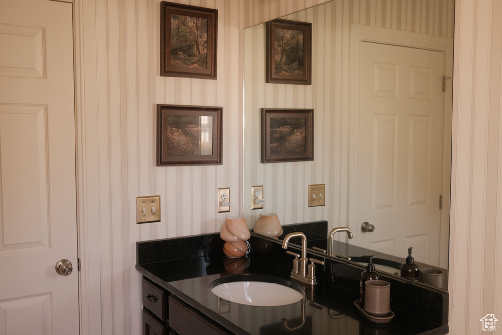 Bathroom featuring wallpapered walls and vanity