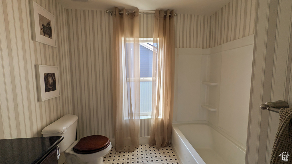 Bathroom featuring wallpapered walls, healthy amount of natural light,  shower combination, and tile patterned floors