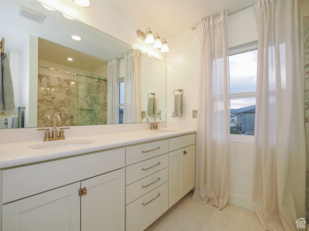 Full bathroom with double vanity, a marble finish shower, tile patterned floors, and recessed lighting