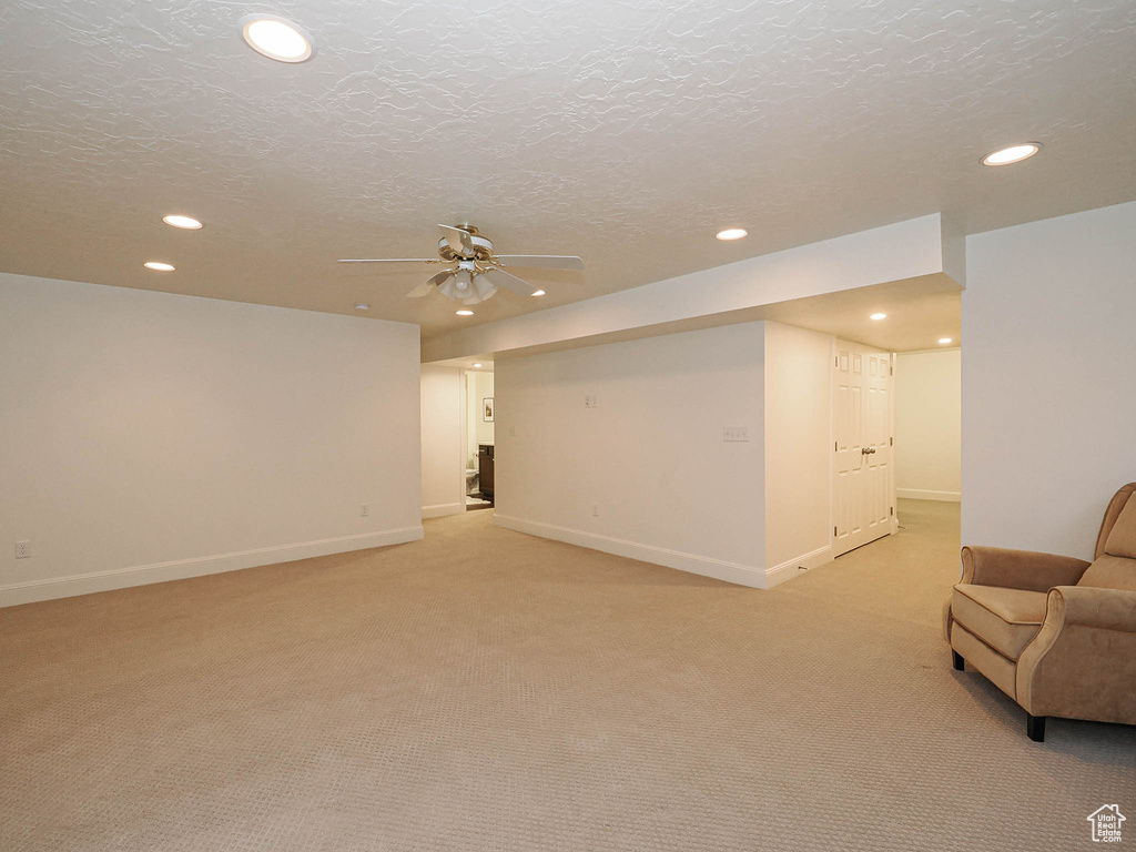 Finished below grade area with recessed lighting, light colored carpet, a textured ceiling, and a ceiling fan