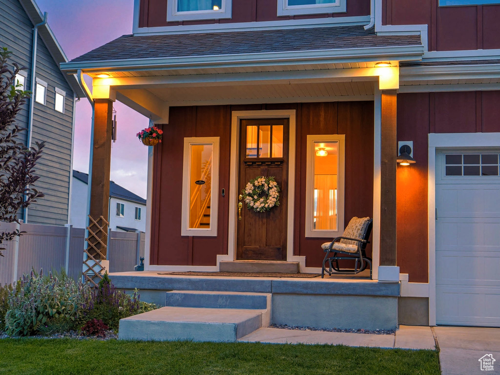 Doorway to property with covered porch, a garage, and board and batten siding