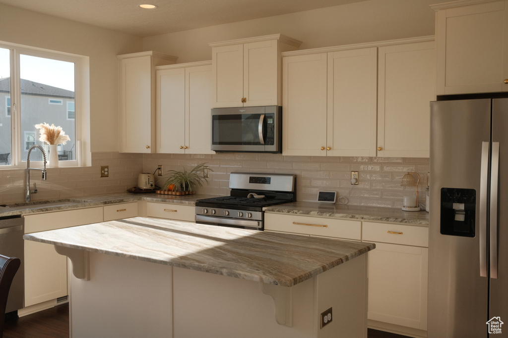 Kitchen featuring appliances with stainless steel finishes, light stone countertops, backsplash, a kitchen island, and recessed lighting