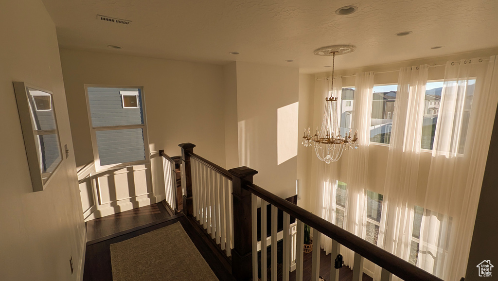 Hallway featuring an upstairs landing and a chandelier