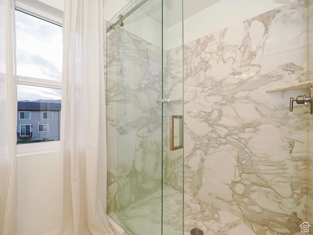 Full bath with a marble finish shower