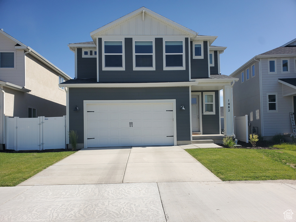 Traditional-style home featuring an attached garage, concrete driveway, board and batten siding, and a gate