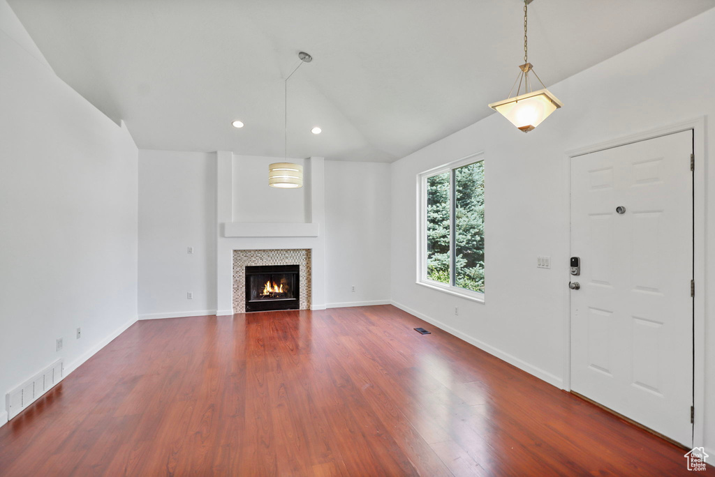 Unfurnished living room with lofted ceiling, dark wood-style floors, a tiled fireplace, and recessed lighting