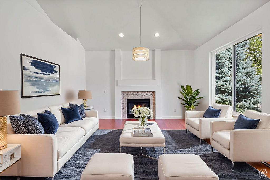 Living area with lofted ceiling, wood finished floors, recessed lighting, and a lit fireplace