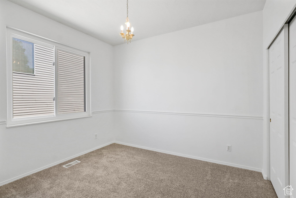 Unfurnished bedroom with carpet flooring, a chandelier, and a closet