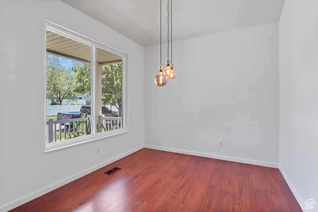 Unfurnished dining area featuring wood finished floors and a chandelier