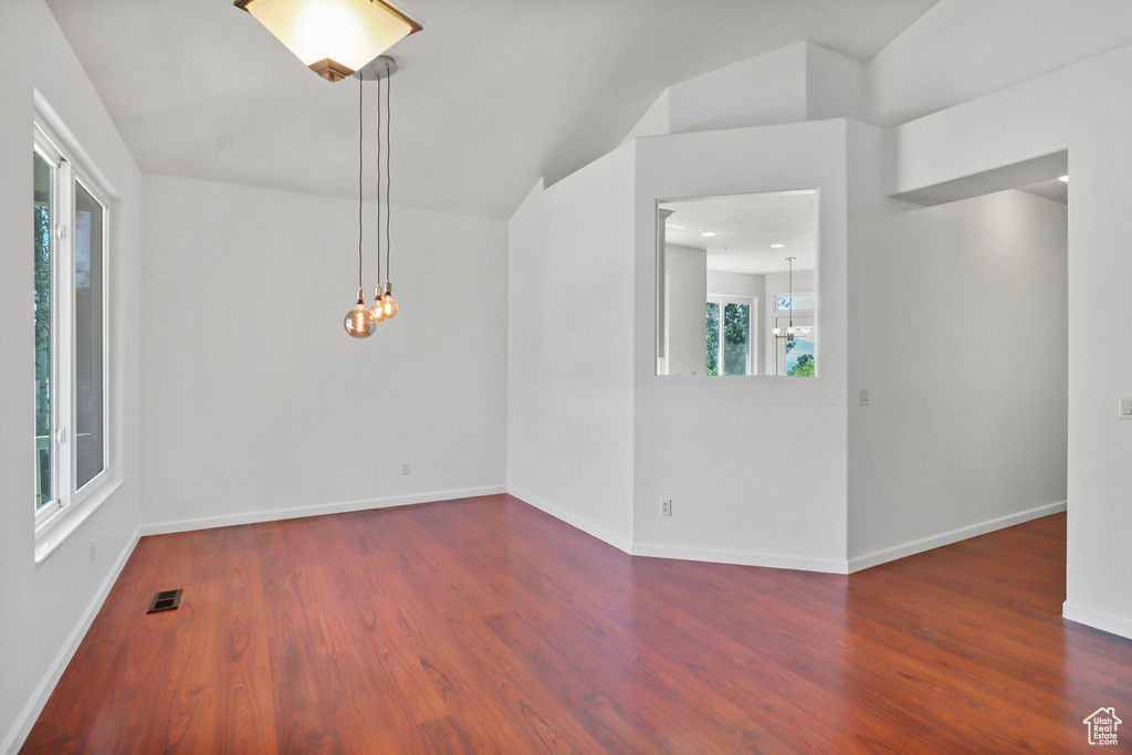 Unfurnished room with a chandelier, wood finished floors, and lofted ceiling