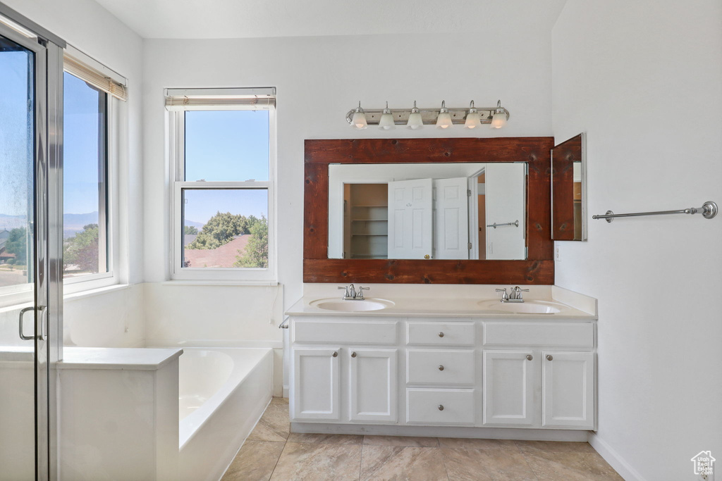 Bathroom featuring plenty of natural light, double vanity, and a garden tub