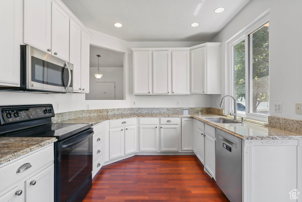 Kitchen featuring appliances with stainless steel finishes, dark wood-type flooring, white cabinets, light stone counters, and recessed lighting