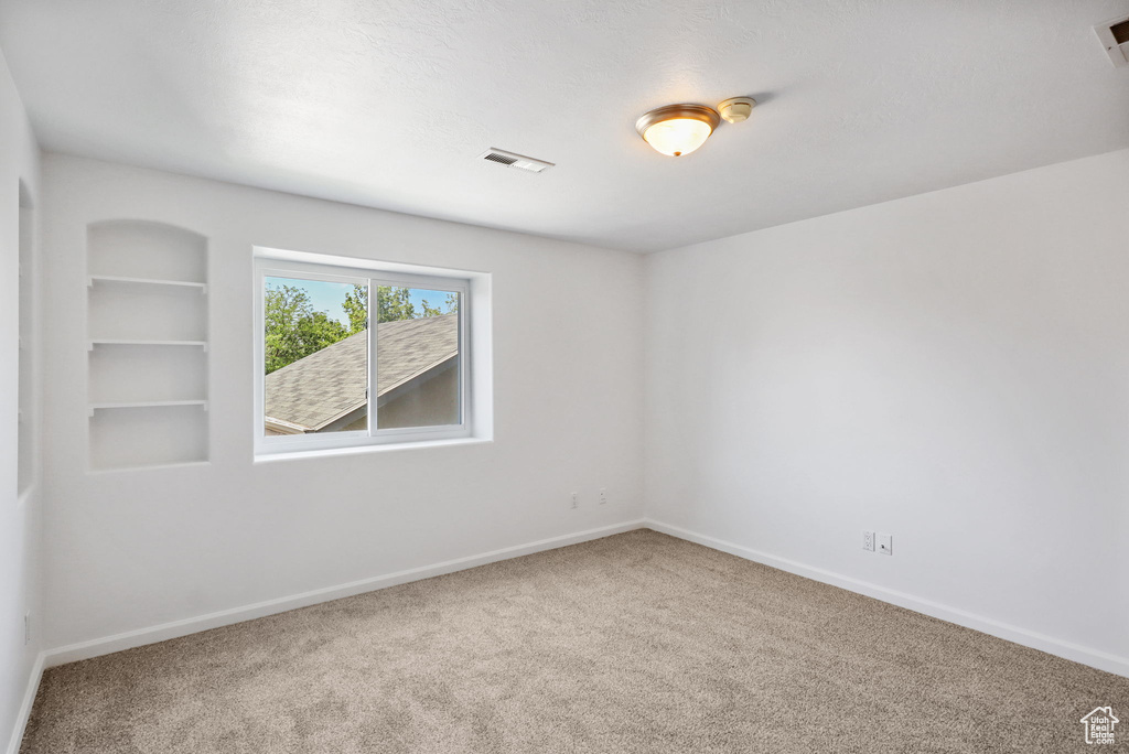 Carpeted spare room with baseboards and a smoke detector