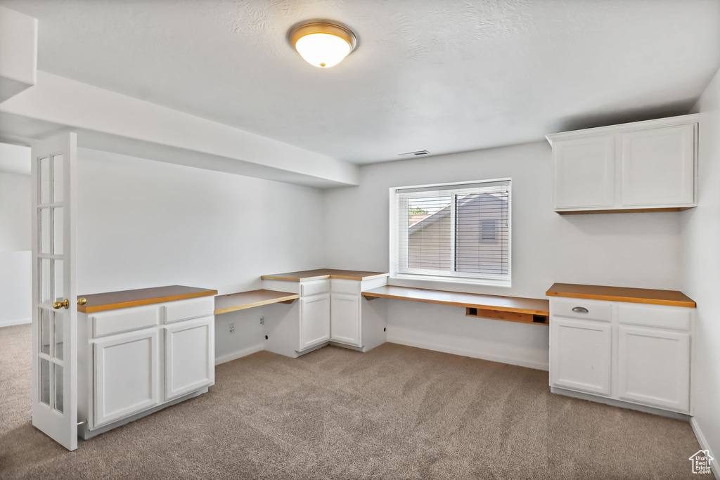 Unfurnished office with built in desk and carpet flooring