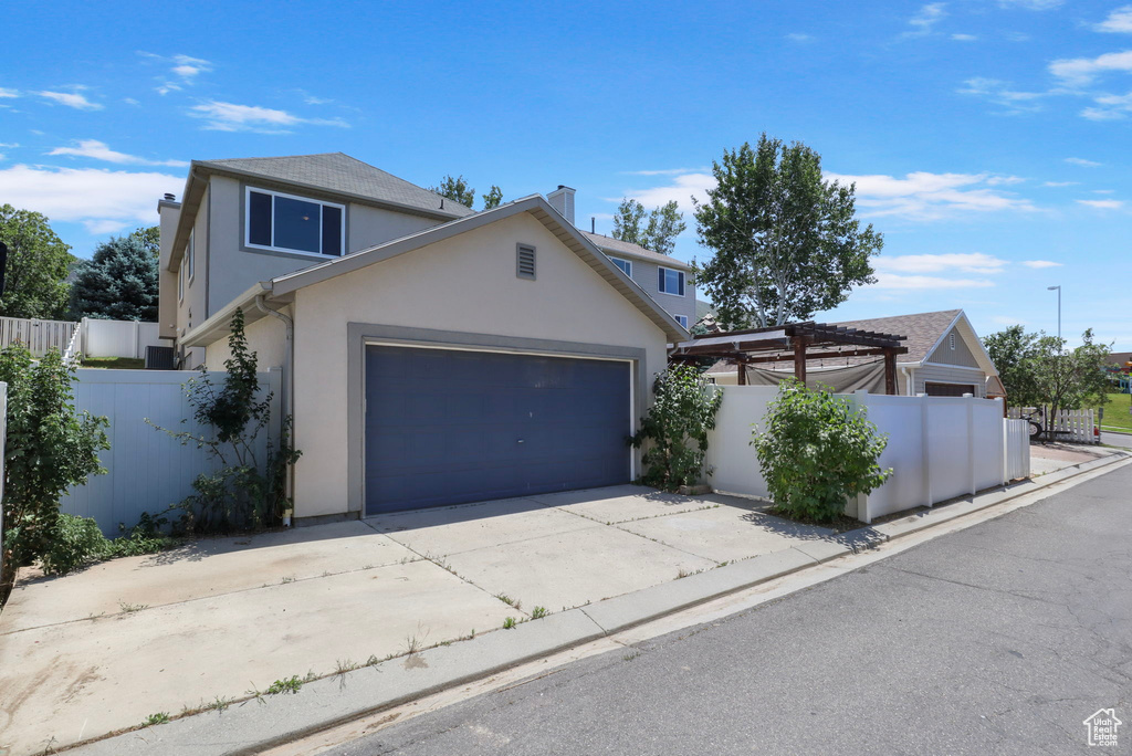 Traditional-style home featuring stucco siding, a chimney, driveway, and an attached garage