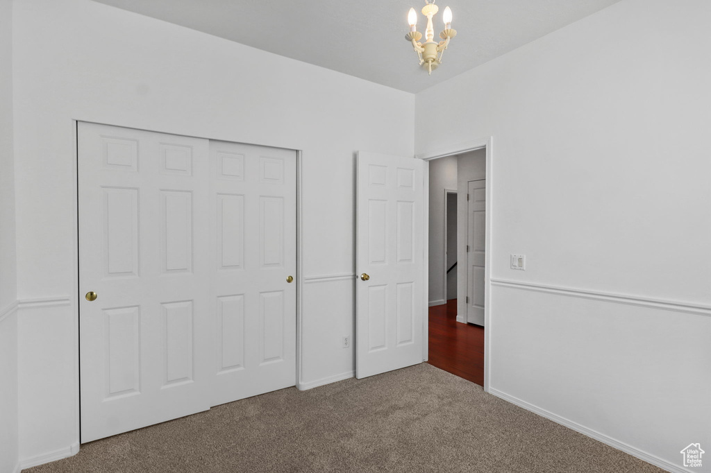 Unfurnished bedroom with a chandelier, carpet, and a closet