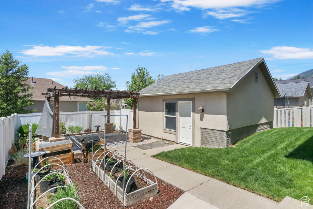 View of outbuilding with a vegetable garden, a fenced backyard, and a pergola